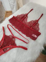 Conjunto de lencería de encaje color rojo, compuesto por un bralette triangular con breteles regulables y una tanga con tiras laterales ajustables.
