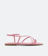 Sandalia plana femenina color rosado, con tiras finas que cruzan sobre el empeine y puntera redonda. Posee un cierre ajustable con hebilla metálica dorada en el tobillo.