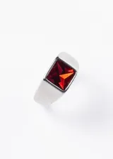 Anillo plateado de acero quirúrgico con piedra roja cuadrada en el centro.