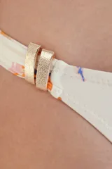 Calzón de bikini de cobertura sutil, color blanco hueso, con estampado abstracto en tonos naranja, azul y rosado. Presenta costuras invisibles y detalles dorados en los laterales.