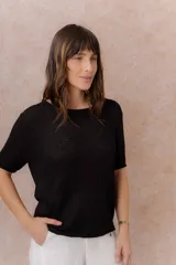 Sweater liviano de punto color negro, de manga corta, con escote redondo y terminaciones con bordes enrollados.