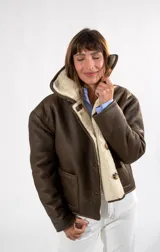 Campera gamulán reversible de cuero color habano con interior de corderito sintético. Presenta cuello solapa, cierre frontal con botones y bolsillos laterales.