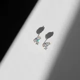 Par de aros dorados con cristales engarzados, uno grande en forma de gota y dos pequeños redondos.