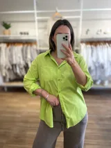 Camisa color verde lima, de corte recto, con cuello camisero, cierre frontal con botones y mangas 3/4.