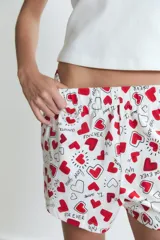 Pijama compuesto por una musculosa blanca de cuello redondo con pequeño bordado en el pecho y un short estampado con corazones rojos y texto sobre fondo blanco, con cintura elástica.