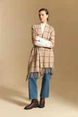 Poncho abierto de tejido de punto con diseño de cuadros grandes en contraste. Presenta un patrón reversible en tonos negro y marrón, con un estilo envolvente y versátil.