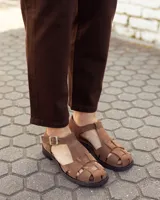 Sandalias de cuero gamuzado color marrón, tipo romanas, con tiras entrelazadas, talón cerrado y tira ajustable con hebilla metálica en el tobillo.