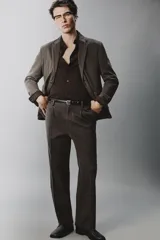 Pantalón relaxed fit de traje color marrón oscuro, confeccionado en tejido con mezcla de algodón. Cuenta con bolsillos frontales, bolsillos traseros de doble vivo con botón y efecto lavado. Cierre frontal con cremallera y botón.