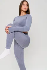 Conjunto deportivo de tres piezas en color lavanda, compuesto por un top de manga larga con orificios para pulgares, un top de bretel ancho y una calza chupín de tiro alto. La prenda presenta un diseño seamless con detalles de texturas perforadas estratégicamente ubicadas para mayor ventilación.