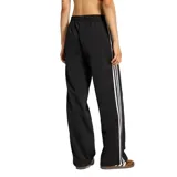Pantalón deportivo Adidas de la línea Originals, confeccionado en tejido tricot de poliéster reciclado. Presenta un corte holgado con cintura media elástica, bolsillos laterales con cierre y el icónico diseño de las tres tiras blancas a lo largo de las piernas.