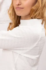 Remera de textura acanalada con cuello medio alto y mangas largas estilo oxford. Diseño básico y versátil de calce ajustado.