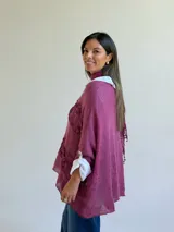 Sweater de punto magenta con diseño holgado, cuello redondo y detalles de encaje floral aplicado en el frente. Incluye una bufanda tipo choker integrada del mismo tejido.