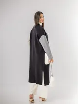 Sacón tipo tapado de corte largo, confeccionado en tejido de punto con diseño color block en tonos gris, negro y blanco. Presenta cierre frontal con botones, bolsillos laterales de parche y aberturas en los costados.