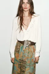 Falda midi plisada con estampado paisley en tonos verde agua, marrón y naranja. Presenta cintura elástica y un cinturón ancho marrón con hebilla dorada.