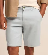 Bermuda slim de sarga color celeste, confeccionada en algodón con elastano. Presenta bolsillos laterales tipo chino, bolsillos traseros embutidos con botón, trabillas en la cintura y cierre frontal con botón y cremallera.