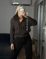 Saco tejido de punto con diseño de ochos, cuello con detalle de piel sintética, cierre frontal con botones al tono y mangas largas.