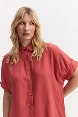 Vestido camisero corto color coral, de silueta amplia y suelta, con manga corta, cuello clásico y cierre frontal de botones.