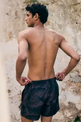 Short de baño con estampado de hojas en tonos oscuros, cuenta con cintura elástica con cordón ajustable, bolsillos laterales y un bolsillo trasero. Incluye suspensor interior de malla.