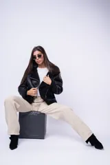 Pantalón de corte baggy color beige, de tiro medio, con bolsillos laterales y costuras verticales decorativas en las piernas.