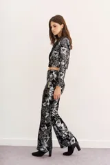 Pantalón de terciopelo negro con estampado floral en plateado, de corte acampanado.