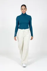 Pantalón de corte recto y tiro alto, confeccionado en pana color crudo. Presenta un diseño de cinco bolsillos, cierre frontal con botón y una cintura con trabillas que incluye un cinturón del mismo tejido con hebilla forrada.