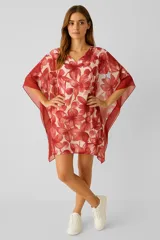 Túnica de corte holgado con cuello en V y mangas tipo kimono. Presenta un estampado floral en tonos rojos sobre fondo claro y bordes en color rojo sólido.