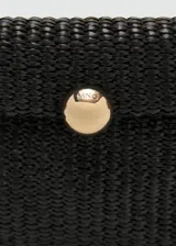 Bolso de mano mediano color negro, confeccionado con tejido trenzado tipo rafia. Cuenta con solapa frontal con cierre de botón a presión metálico dorado, asa de muñeca desmontable y detalle de logo grabado en dorado.