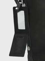 Cartera tipo tote de la marca Hush Puppies, color negro, con diseño minimalista y correa ajustable. Incluye un colgante decorativo con el logo del perro característico de la marca.