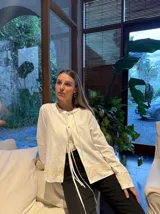 Camisa blanca de mangas largas con detalle de encaje en ruedo y puños, con lazo en el cuello.