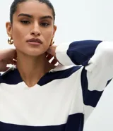 Suéter de punto con diseño de rayas horizontales anchas en color verde oscuro y blanco. Presenta cuello tipo polo con escote en V, mangas largas con puños ajustados y un corte regular.