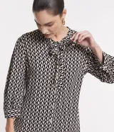 Vestido chemise midi de viscosa con estampado geométrico en blanco y negro. Tiene lazo en el cuello, abotonadura frontal y mangas 3/4.