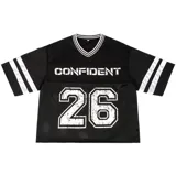 Remera estilo jersey deportiva, color negro, corte boxy y cuello V con ribete blanco. Presenta la palabra "CONFIDENT" estampada en blanco en el pecho y el número "26" grande con efecto desgastado en la parte inferior. Las mangas cortas tienen tres franjas blancas.