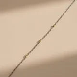 Pulsera de cadena fina de plata con pequeñas cuentas esféricas de oro distribuidas a lo largo de la pieza.