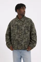 Campera de algodón con diseño estampado de camuflaje en tonos verde militar, con cuello camisero, cierre frontal y bolsillos laterales.
