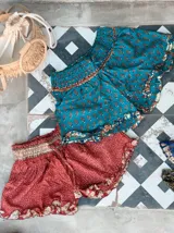 Short de seda con elástico fruncido en la cintura y volado en el ruedo. Presenta un estampado vibrante en tonos rojo/bordó y turquesa con motivos florales o arabescos.