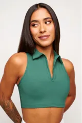 Top deportivo color verde bosque, estilo crop top, con cuello polo y escote pronunciado en V sin mangas.