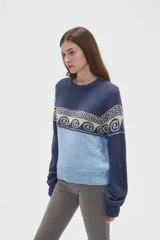 Sweater de tejido de punto con diseño jacquard, cuello redondo y mangas largas. Presenta una combinación de bloques de color azul marino y celeste con un patrón geométrico en la parte superior.