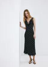 Vestido midi negro con estampado de lunares blancos, escote en pico con detalle de encaje, tirantes y diseño fluido de corte recto.