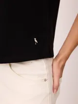Remera blanca de manga corta con vuelta en los puños y detalle de botón dorado. Presenta cuello redondo y corte recto.