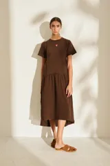 Vestido midi color crudo de manga corta, con corte en la cintura y falda holgada con volados y detalle de pequeño bordado de hongo en el pecho.