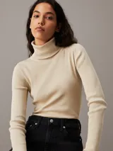 Sweater ajustado de punto de canalé color crema, con cuello alto y logo bordado en el ruedo.