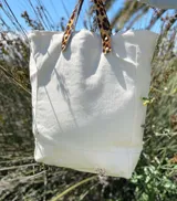 Bolso tote de loneta color crudo con base reforzada y asas cortas de cuero con estampado animal print.