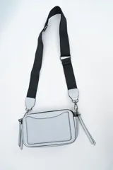 Bandolera de diseño rectangular en color negro, confeccionada en material texturizado. Cuenta con una correa de hombro ajustable y extraíble, cierre superior y tiradores laterales decorativos.