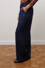 Pantalon de corte recto y pierna ancha, confeccionado en tejido tipo denim oscuro. Presenta tiro alto, cintura con cierre frontal y bolsillos laterales funcionales.