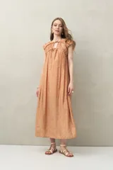 Vestido largo con estampado geométrico en tonos azul, marrón y beige. Tiene escote en V con lazos ajustables, mangas cortas y corte holgado.