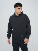 Canguro de felpa Umbro color negro con capucha, cordones de ajuste, bolsillo tipo canguro y etiqueta con logo de la marca en la parte frontal inferior.