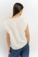 Remera sin mangas de corte holgado, con hombreras marcadas que crean un efecto de manga corta estructurada. Presenta un diseño minimalista con frunces laterales en la cintura y cuello redondo.