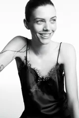 Vestido corto de satén con escote en pico y tirantes finos. Presenta aplicaciones de encaje en el escote y en el bajo, con un diseño asimétrico y abertura lateral.