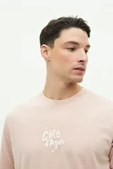 Remera de manga corta color verde agua con estampado gráfico en la espalda que incluye texto y motivos playeros. Confeccionada en algodón con calce regular.