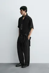 Camisa de corte relajado confeccionada en tejido fluido con textura acanalada. Presenta cuello solapa, manga corta y cierre frontal con botones.